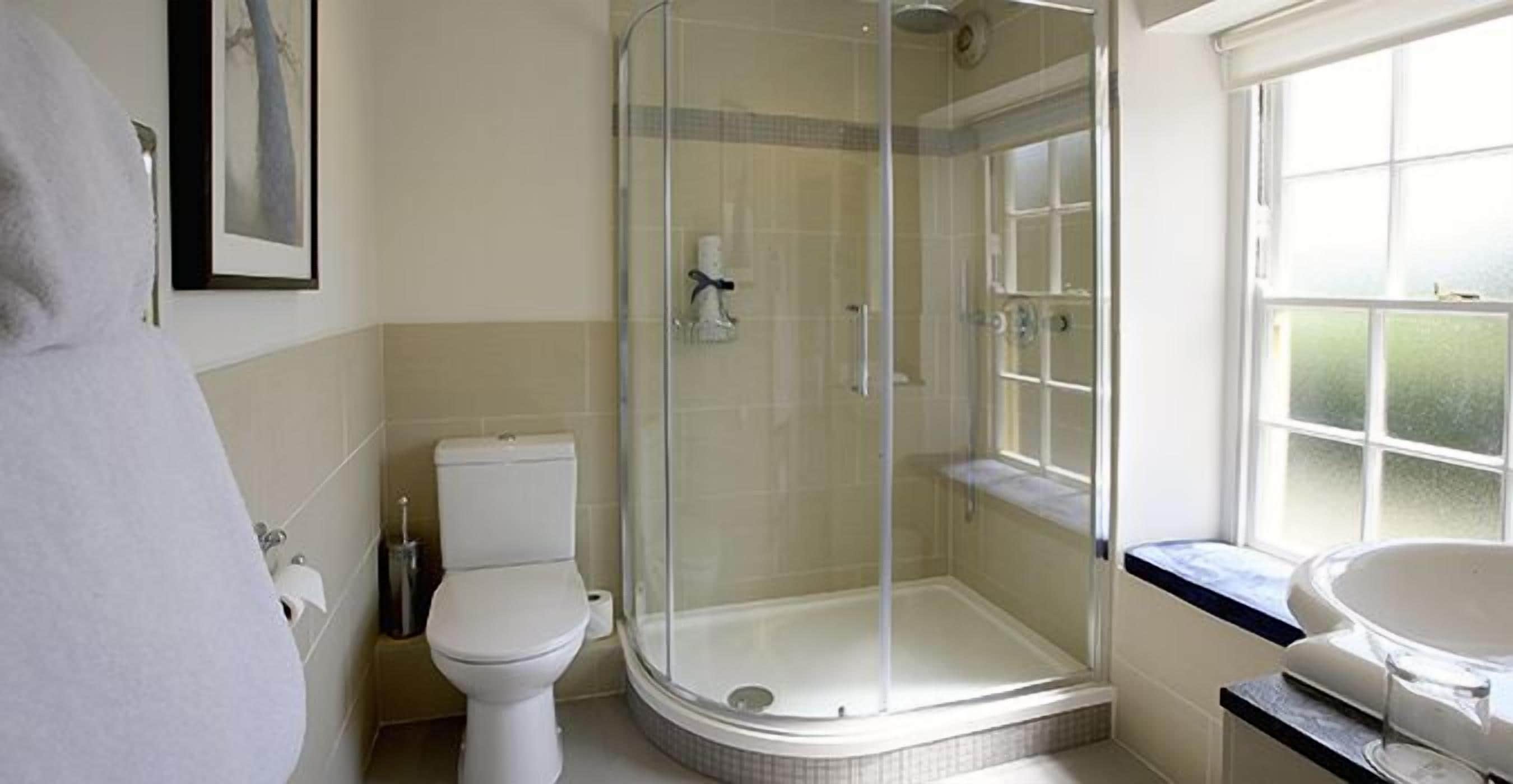 A bathroom with a glass-enclosed shower, a toilet, and a sink.