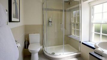 A bathroom with a glass-enclosed shower, a toilet, and a sink.