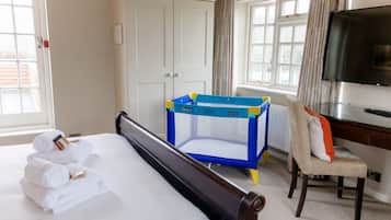 Een hotelkamer met een bed, een kinderbedje, een bureau en een televisie.