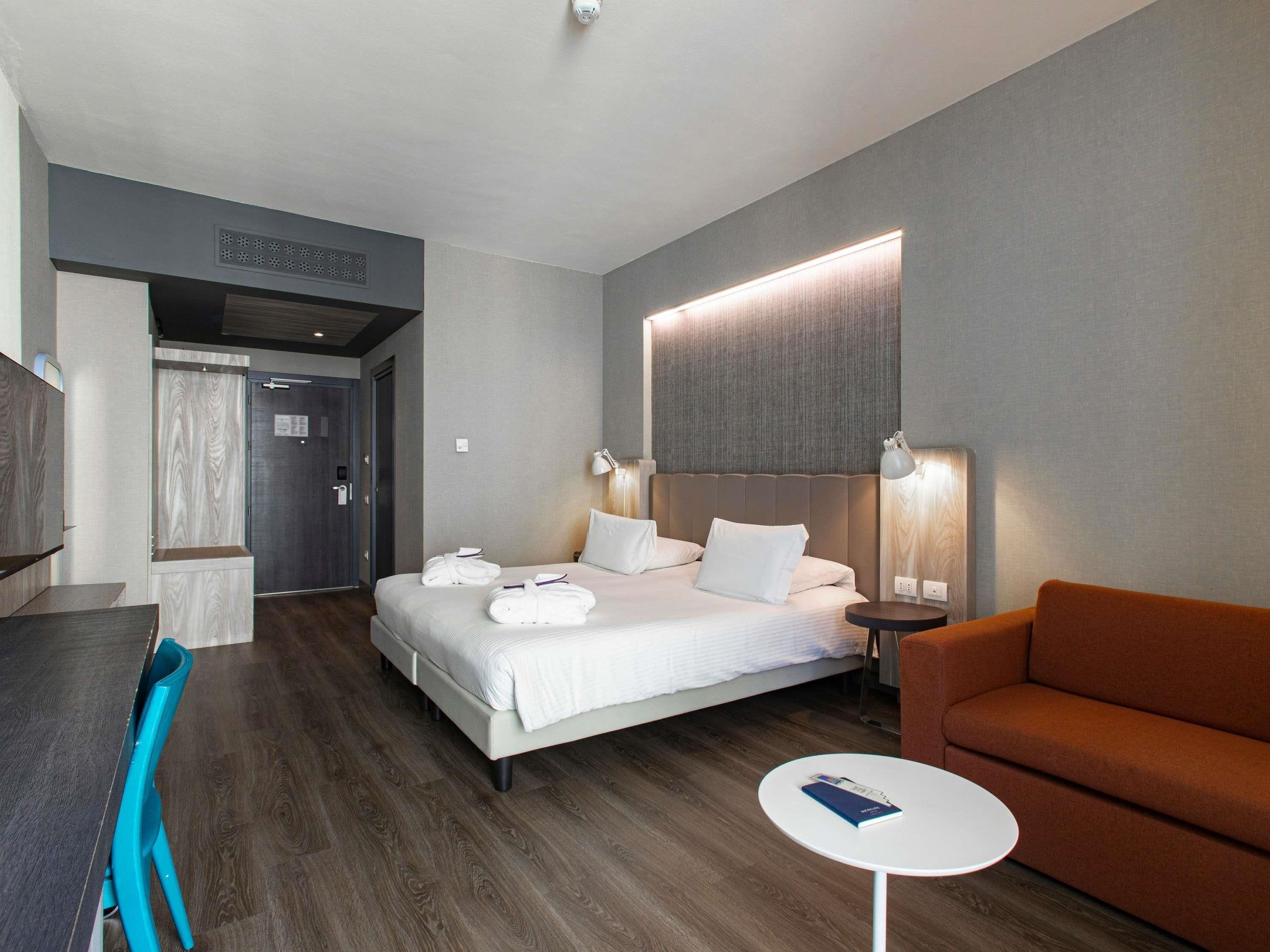 Una habitación de hotel moderna con una cama grande, un escritorio, una silla y una mesita redonda.