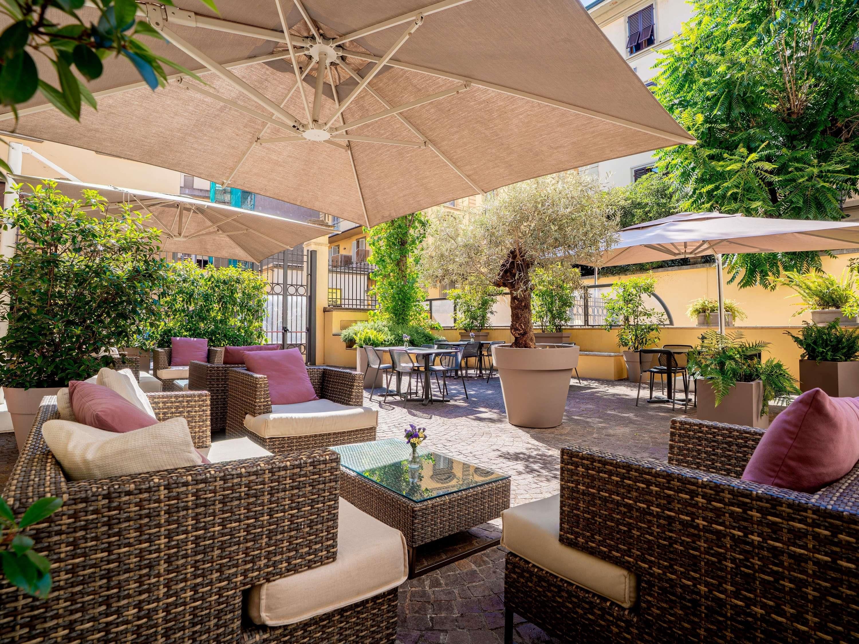 Un espace extérieur aménagé avec des meubles en osier, des parasols et des plantes en pot.