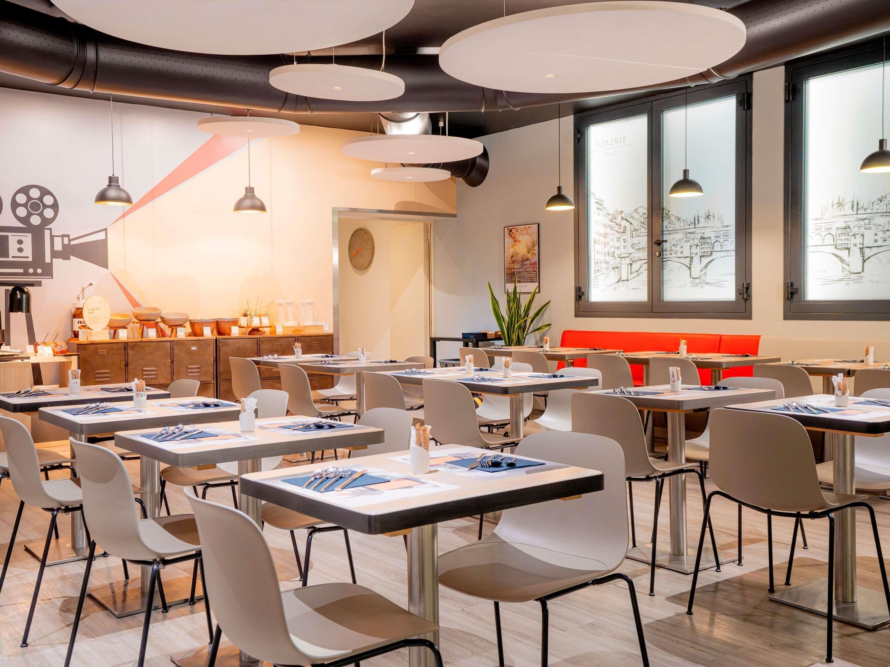A modern restaurant interior with round tables, chairs, and pendant lighting.