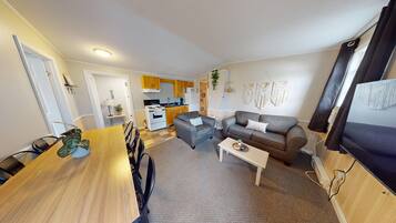 A compact living space with a dining area, a sofa, and a kitchen in the background.