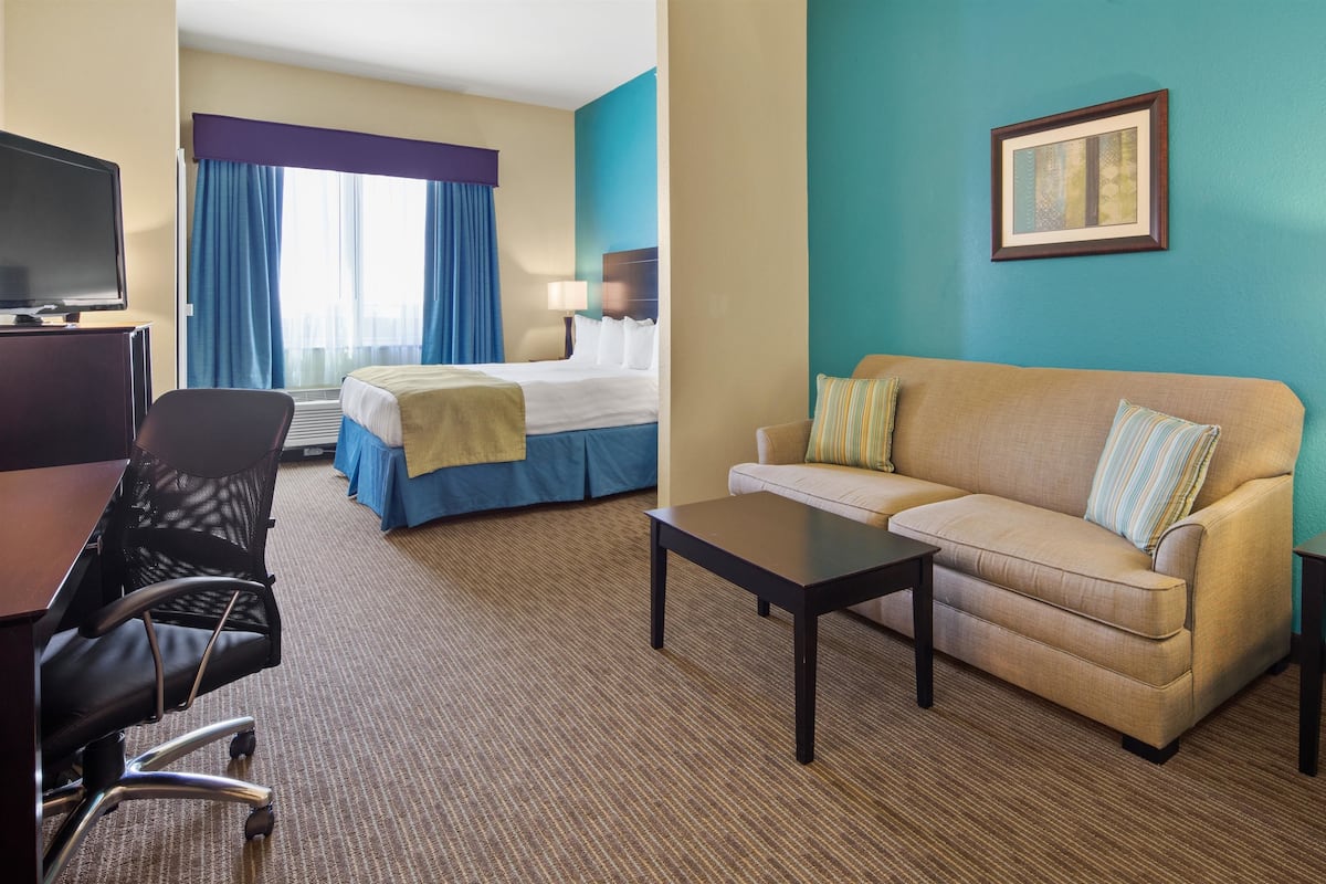 Ein Hotelzimmer mit einem Bett, einem Sofa, einem Schreibtisch, einem Sessel und einer Lampe.