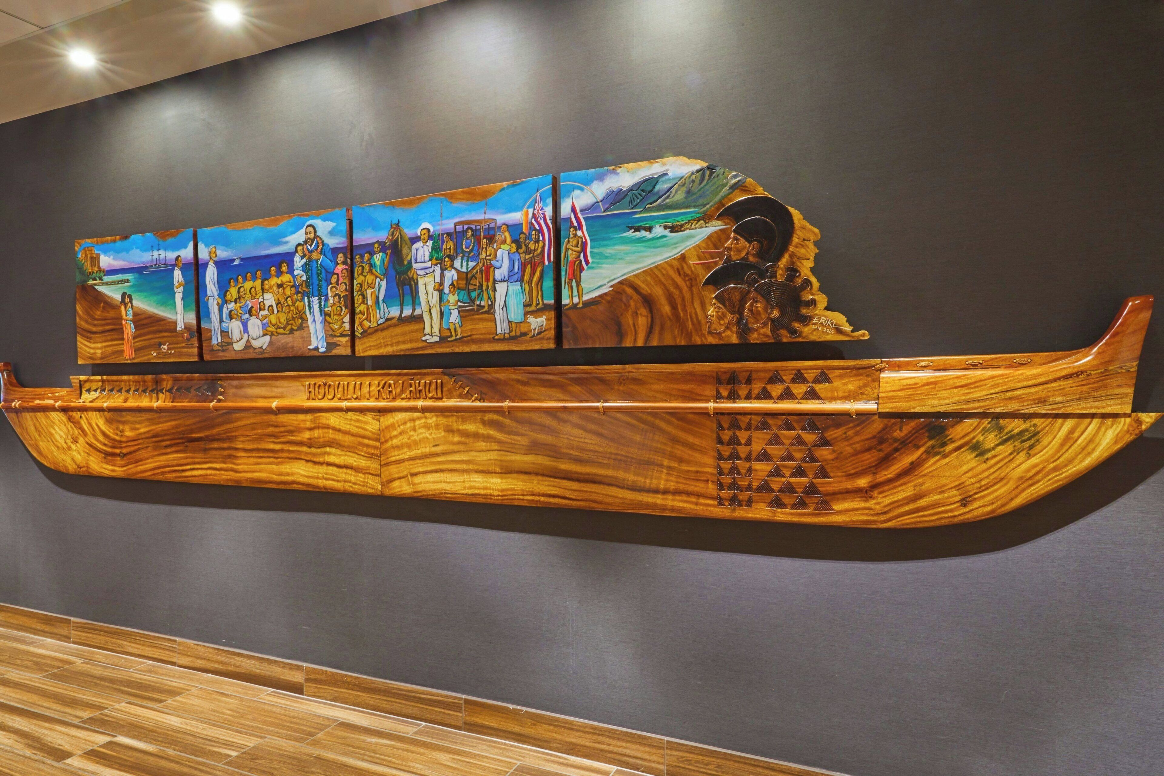 A wooden boat-shaped artwork with a group of people on a beach scene.