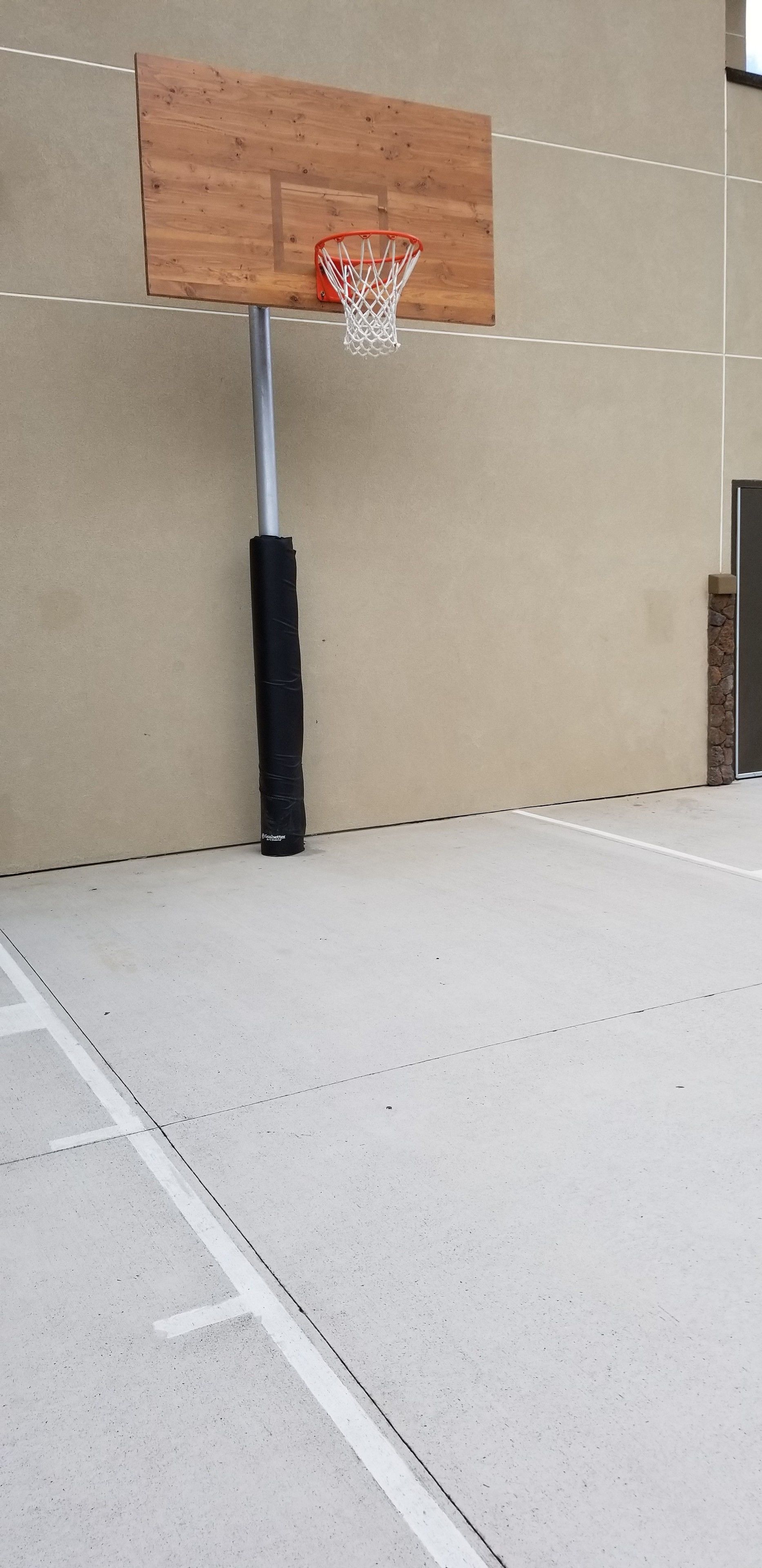 A basketball hoop mounted on a wall with a concrete floor.