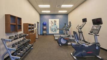 A gym with treadmills, elliptical machines, and dumbbells.