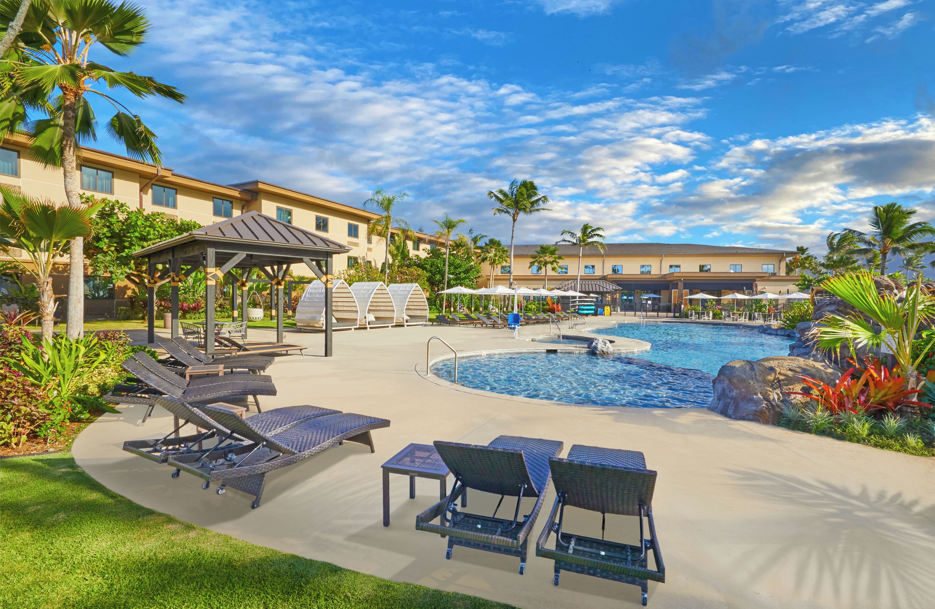 A pool area with lounge chairs, a gazebo, and a building in the background.