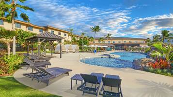 A pool area with lounge chairs, a gazebo, and a building in the background.