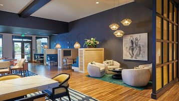 Un'ampia hall con pavimento in legno, zone relax e lampadari a sospensione.
