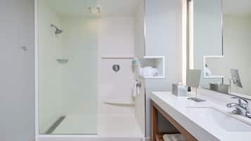 A modern bathroom with a glass-enclosed shower, a white sink, and a large mirror.