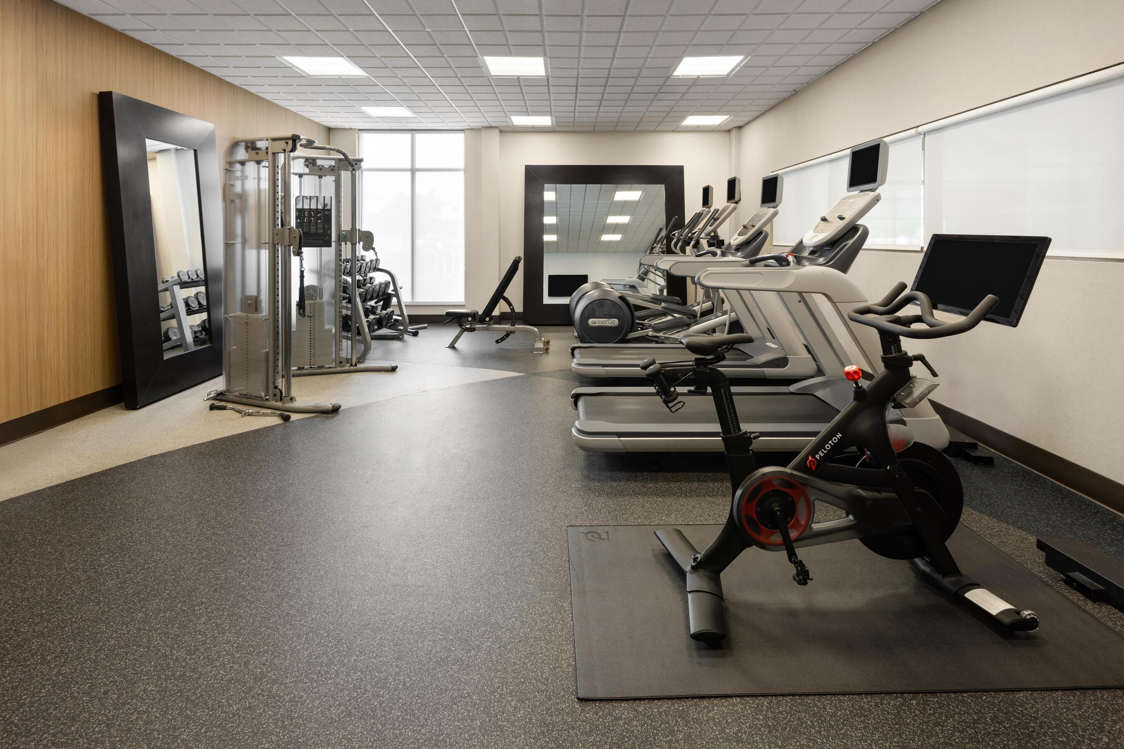 A gym with cardio machines, weightlifting equipment, and mirrors.