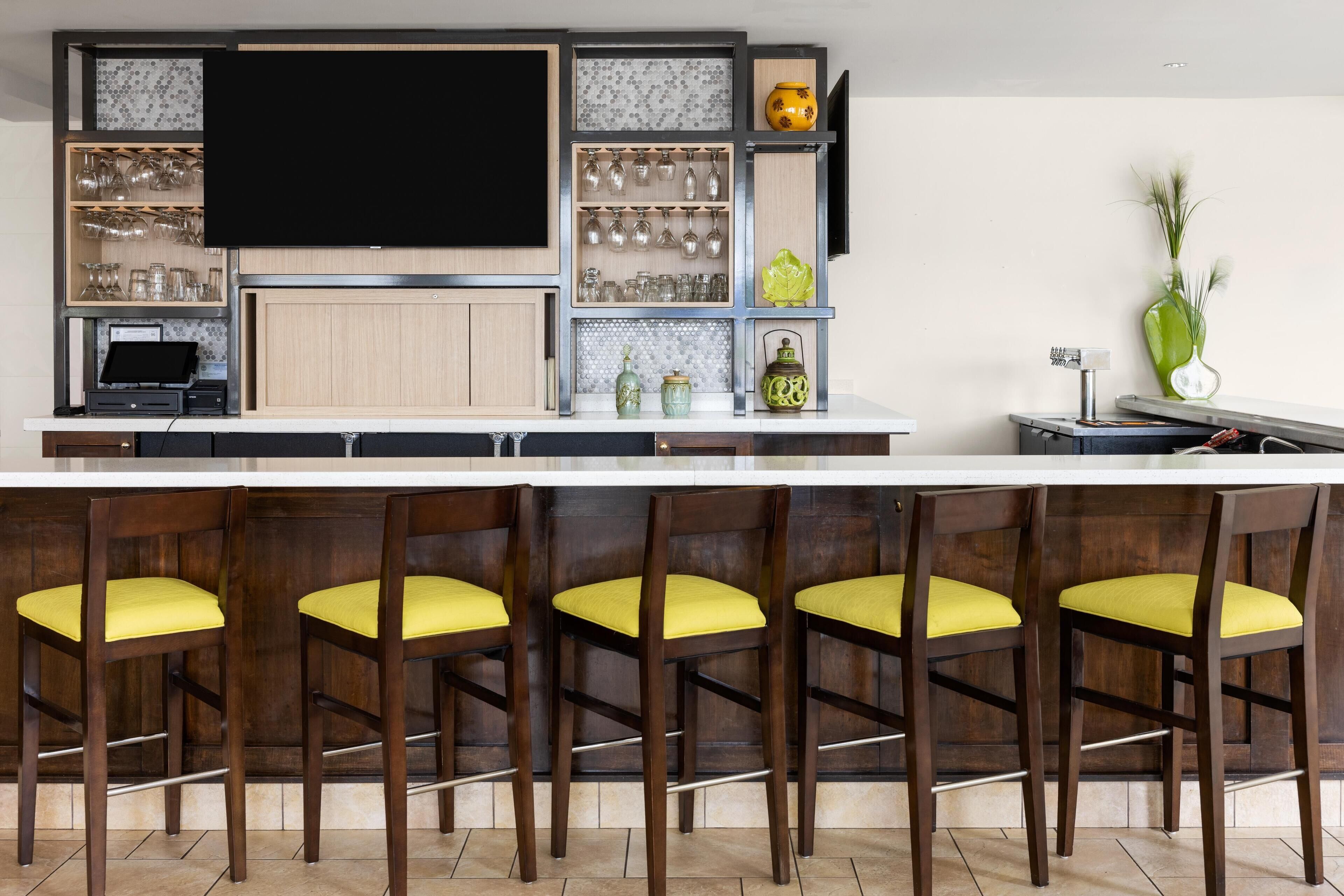 A modern kitchen with a large island, bar stools, and various kitchenware.