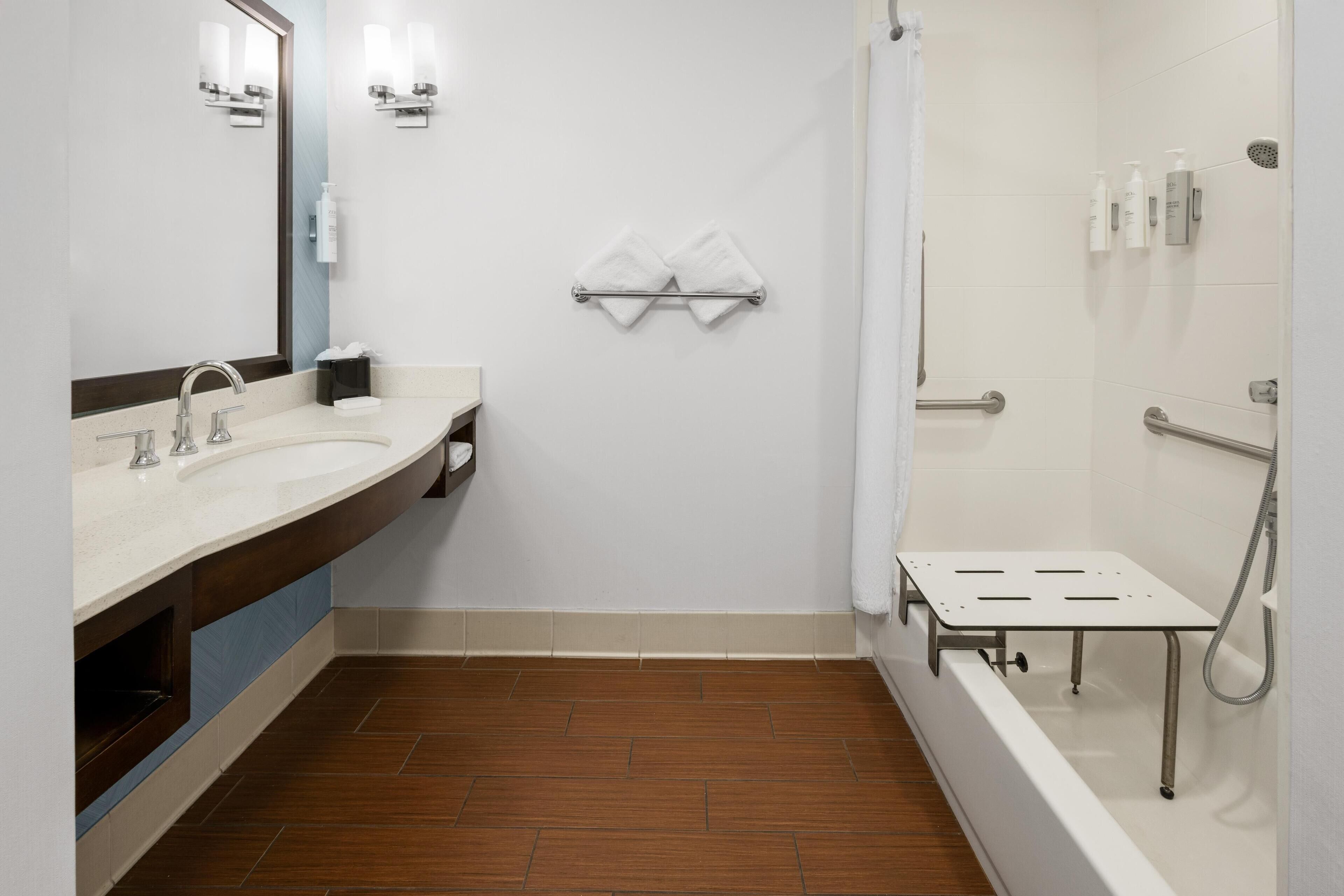 A modern bathroom with two sinks, a shower, and a vanity with a mirror.