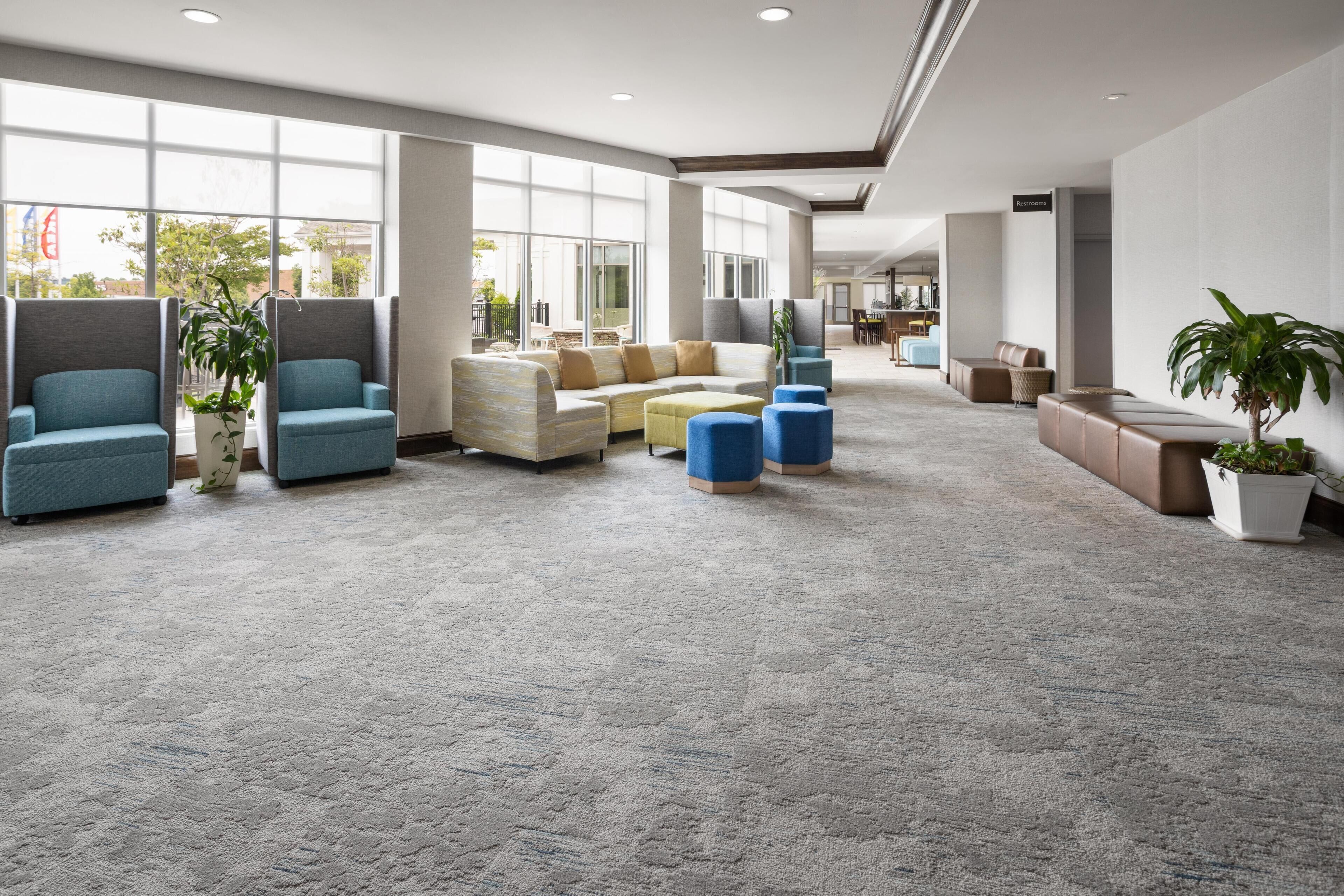 A spacious lobby with seating areas, large windows, and a carpeted floor.