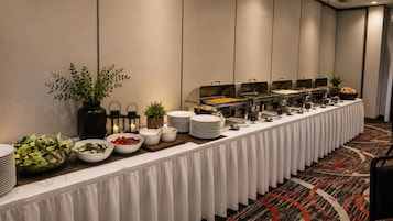Una mesa larga cubierta con un mantel blanco, con una variedad de alimentos en estilo bufé.