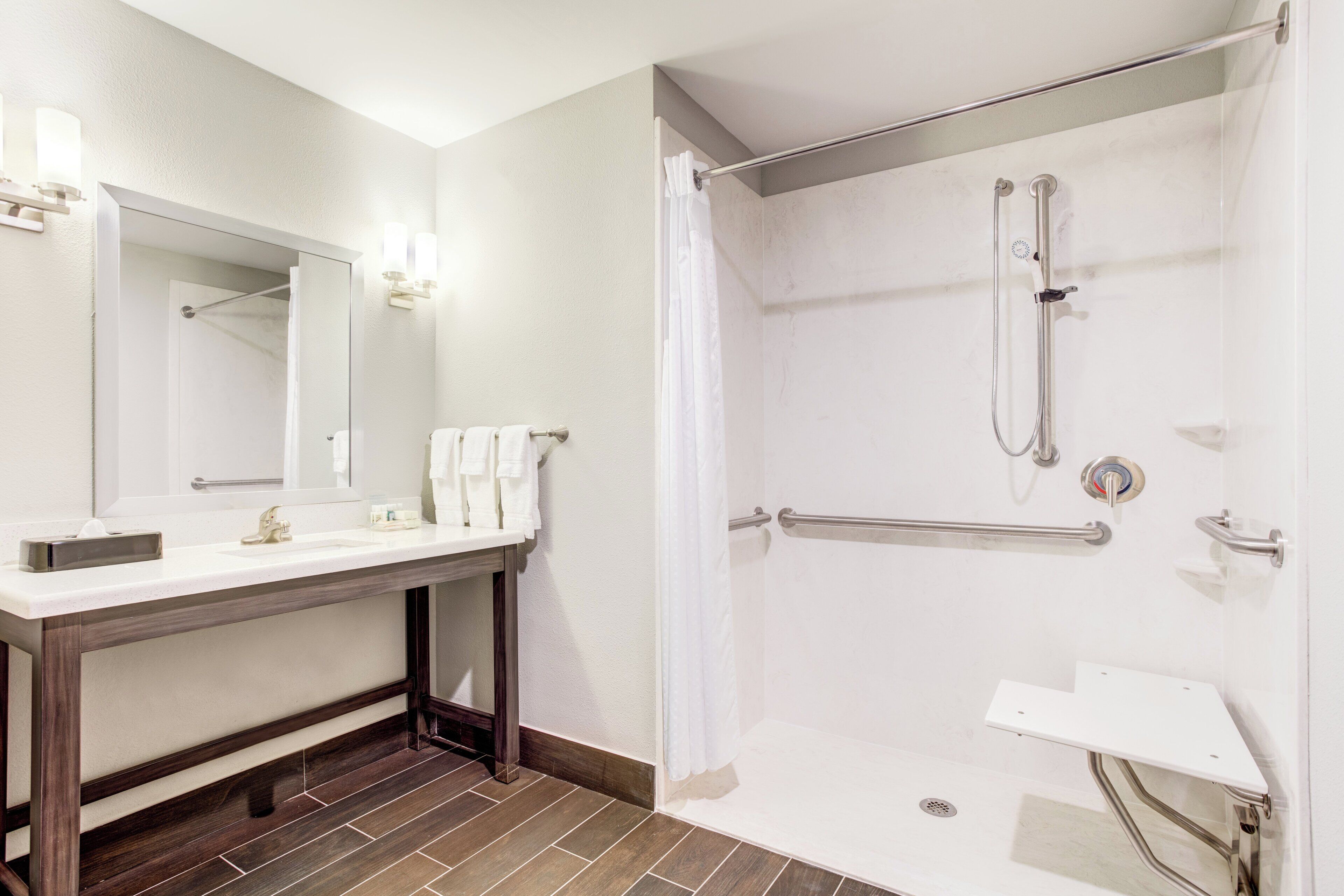 Un bany modern amb dutxa, un lavabo amb mirall i un vàter.