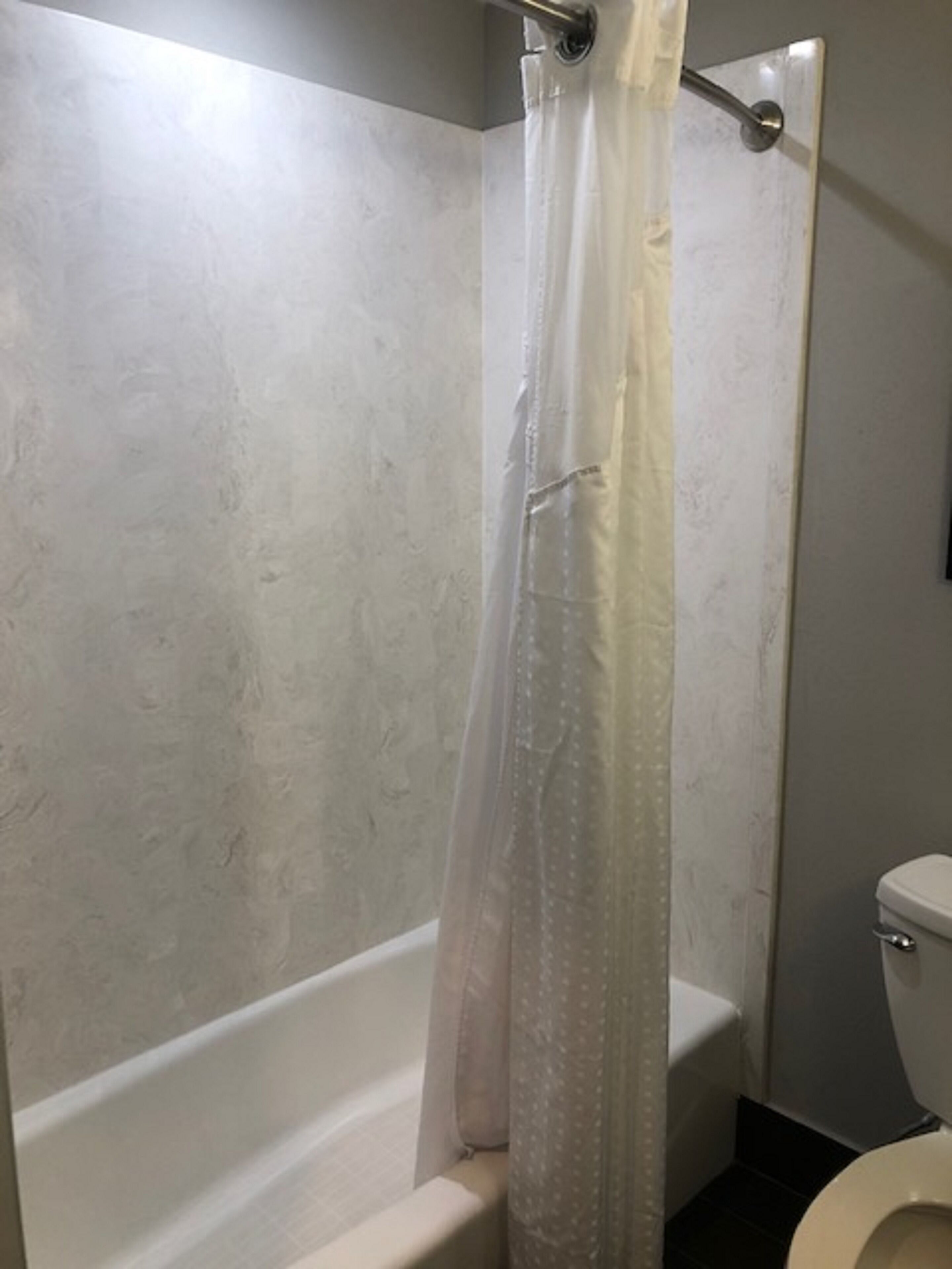 Um banheiro com banheira, vaso sanitário e cortina de chuveiro.