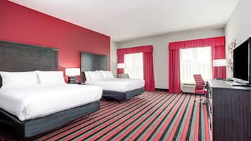Een hotelkamer met twee bedden, een bureau, een televisie en een rood-gestreept tapijt.