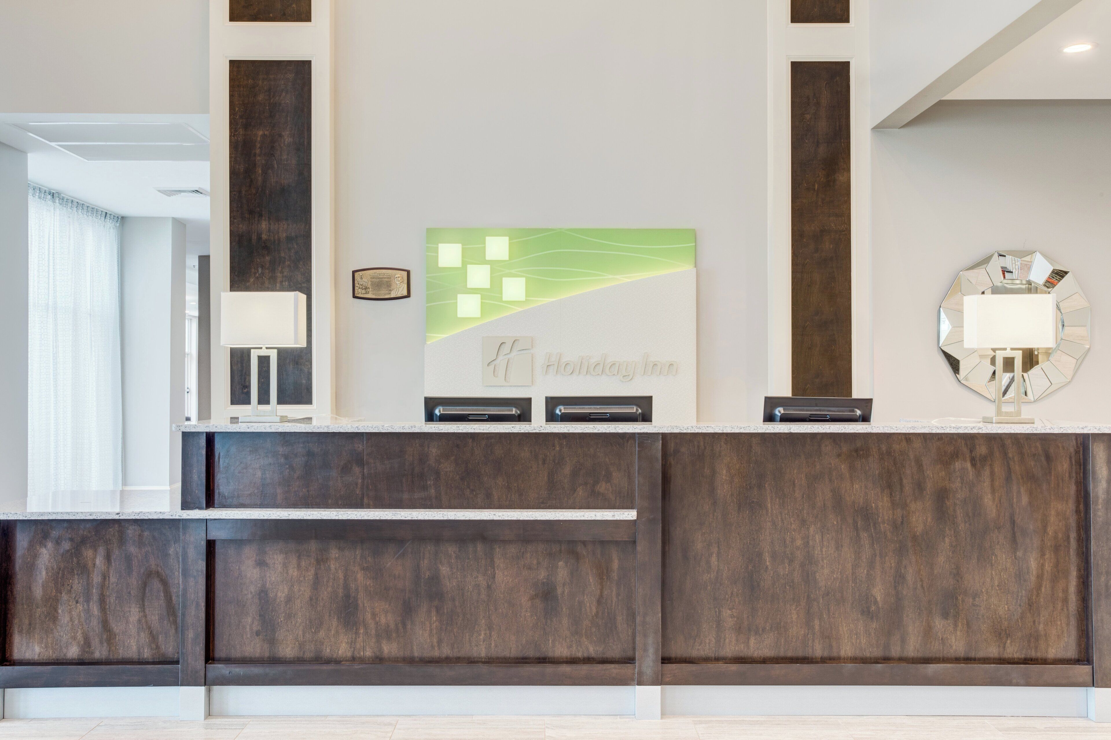 A reception desk with a modern design, a framed certificate, and a decorative wall piece.