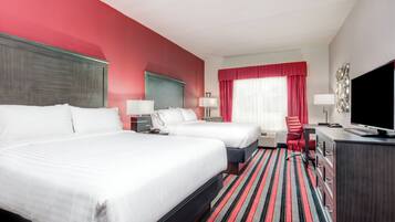 A hotel room with two beds, a desk, a chair, a TV, and a window with curtains.