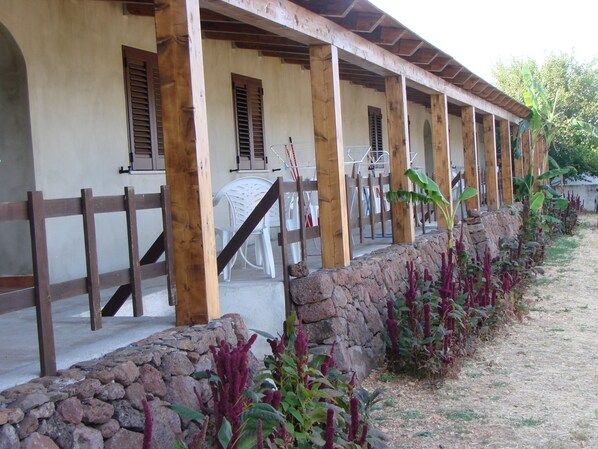 A covered outdoor seating area with stone walls and plants.