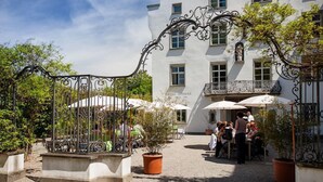 Un patio con asientos al aire libre, una reja de hierro forjado y un edificio con un balcón.