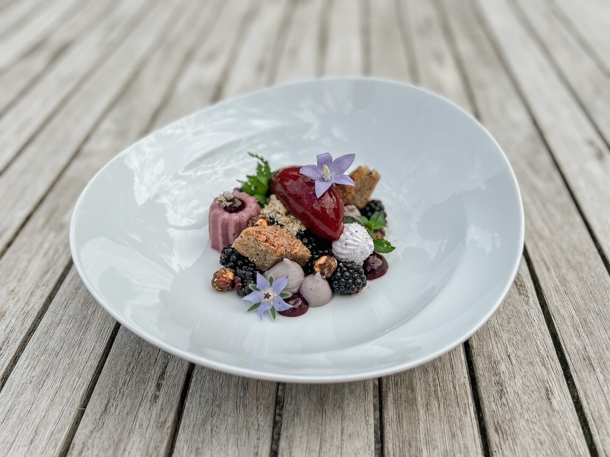 En hvid tallerken med dessert på et træbord.