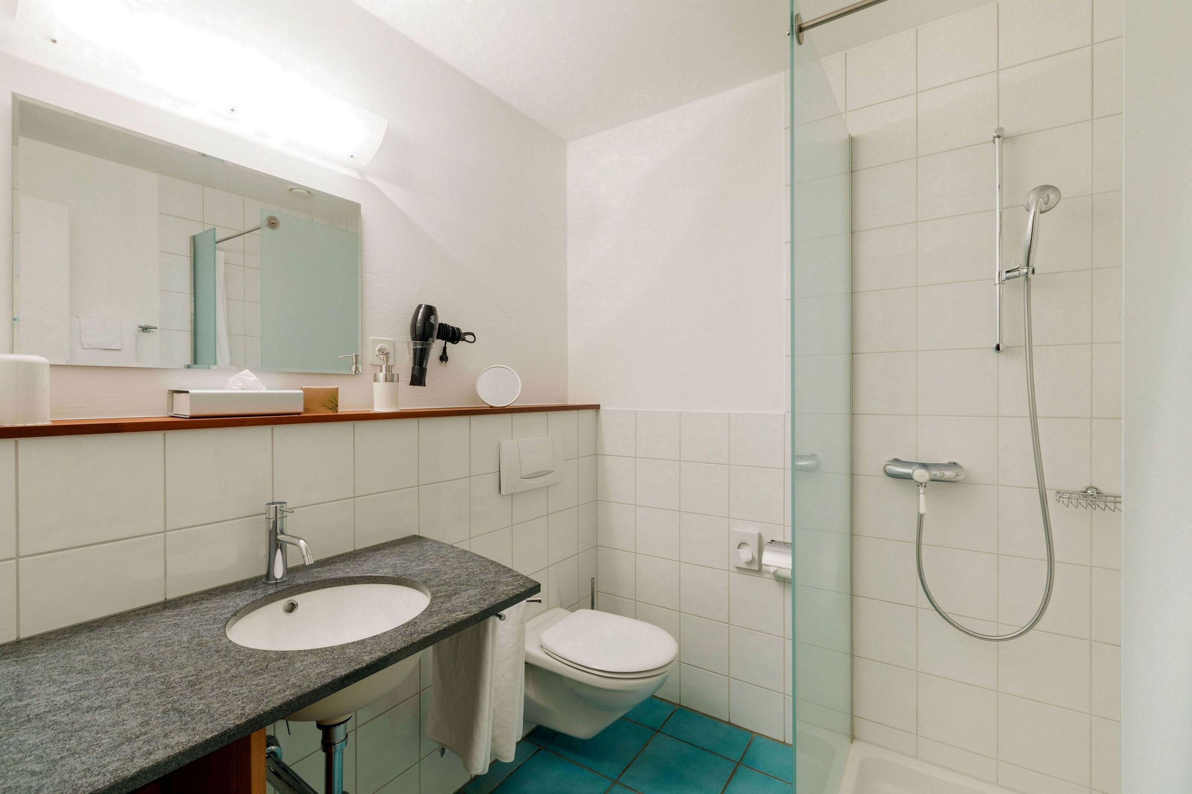 Un baño con lavamanos, inodoro y ducha.