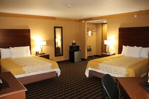 A hotel room with two beds, a desk, a chair, a mirror, a TV, and a small trash bin.