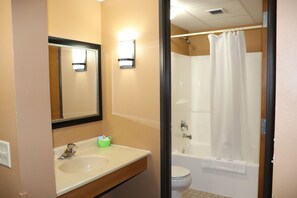 A bathroom with a sink, mirror, and a shower area.
