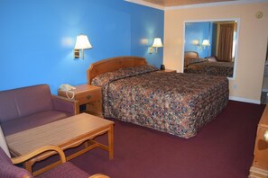 A hotel room with a bed, a sofa, a desk, and a nightstand.
