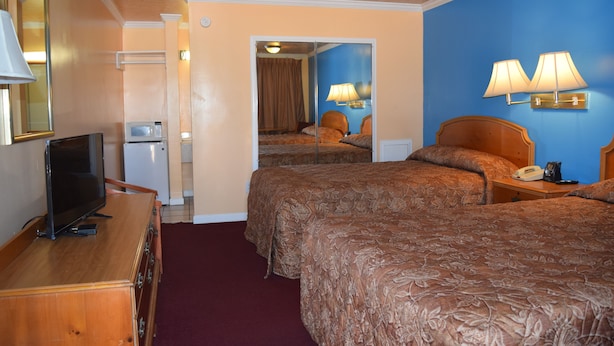 A hotel room with two beds, a television on a wooden dresser, a microwave, and a telephone. - Fort Eustis Inn (Newport News)