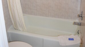 A bathroom with a bathtub, toilet, and tiled walls. - Fort Eustis Inn (Newport News)
