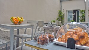 Una mesa con un frutero, frascos de nueces y una bandeja cubierta de pasteles.