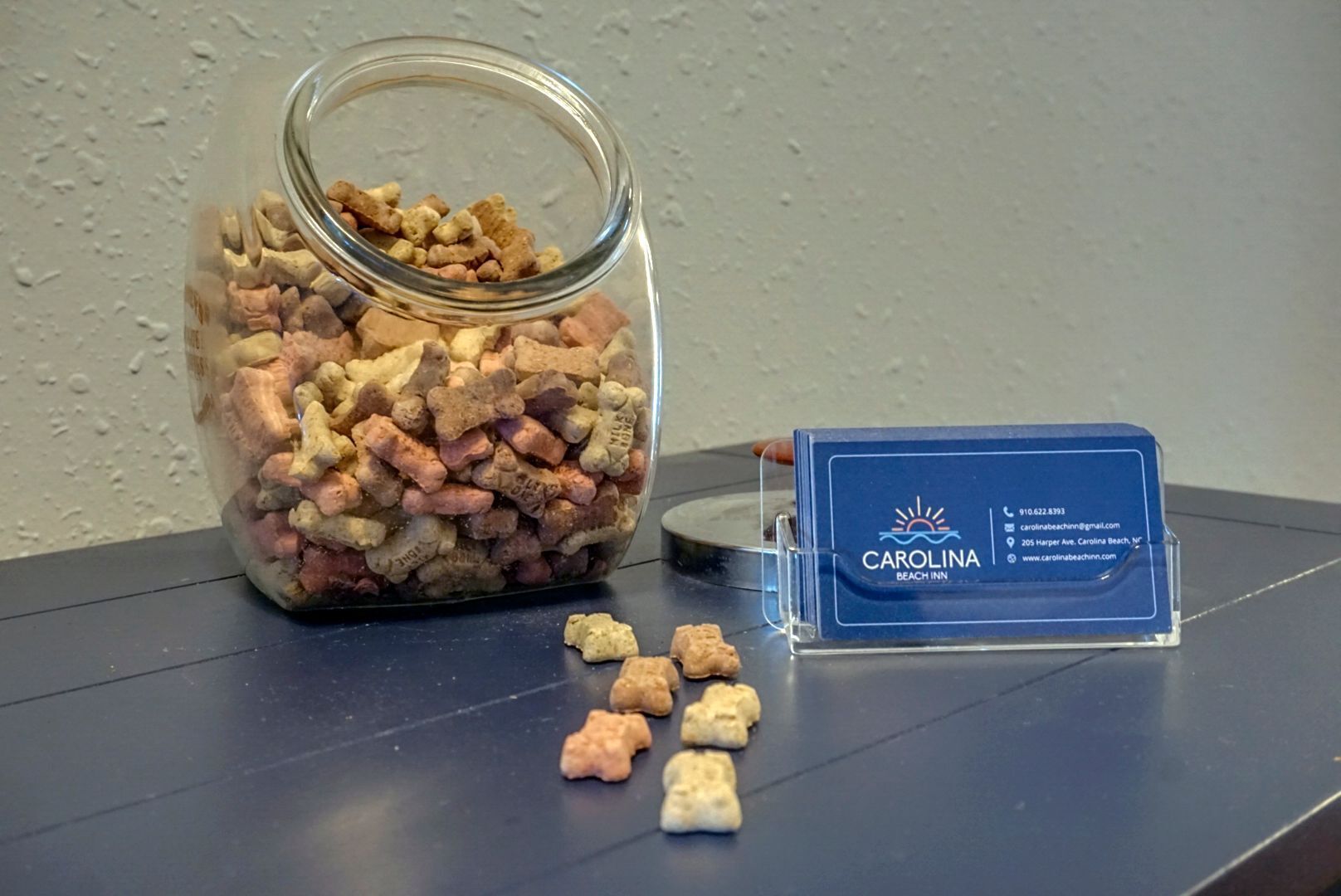 Un barattolo di vetro pieno di snack per animali domestici e un biglietto da visita del Carolina Beach Inn.