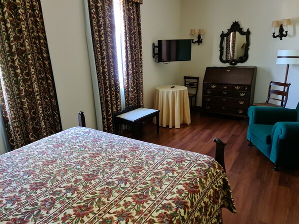 A hotel room with a bed, a small table, a dresser, a chair, and a TV.