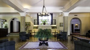 A spacious lobby with a large chandelier, multiple armchairs, a central potted plant, and a patterned rug on the floor. - Hotel Urgeiriça (Nelas)