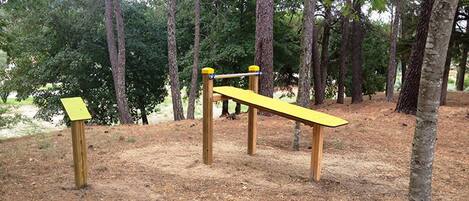 Un parque infantil con un sube y baja y una estructura para escalar en un área boscosa.