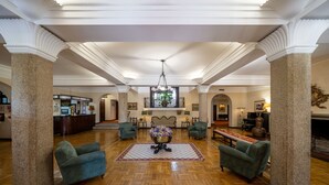 A spacious lobby with high ceilings, large columns, and a central area with a chandelier, sofas, and a decorative table. - Hotel Urgeiriça (Nelas)