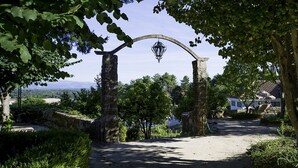 A pathway leading through a garden with a stone archway and a hanging lantern. - Hotel Urgeiriça (Nelas)