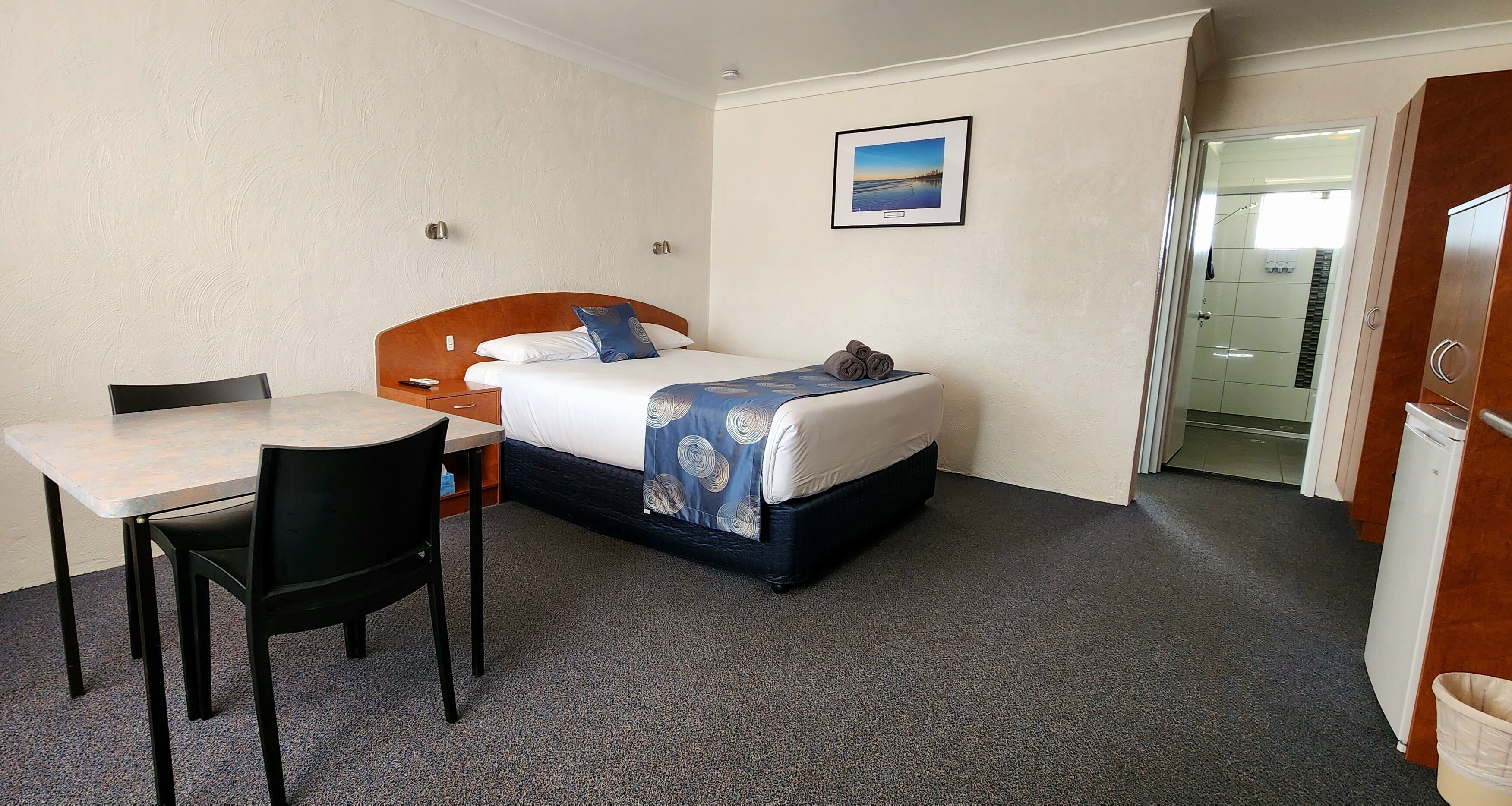 Et hotelværelse med en seng, et skrivebord og en stol.