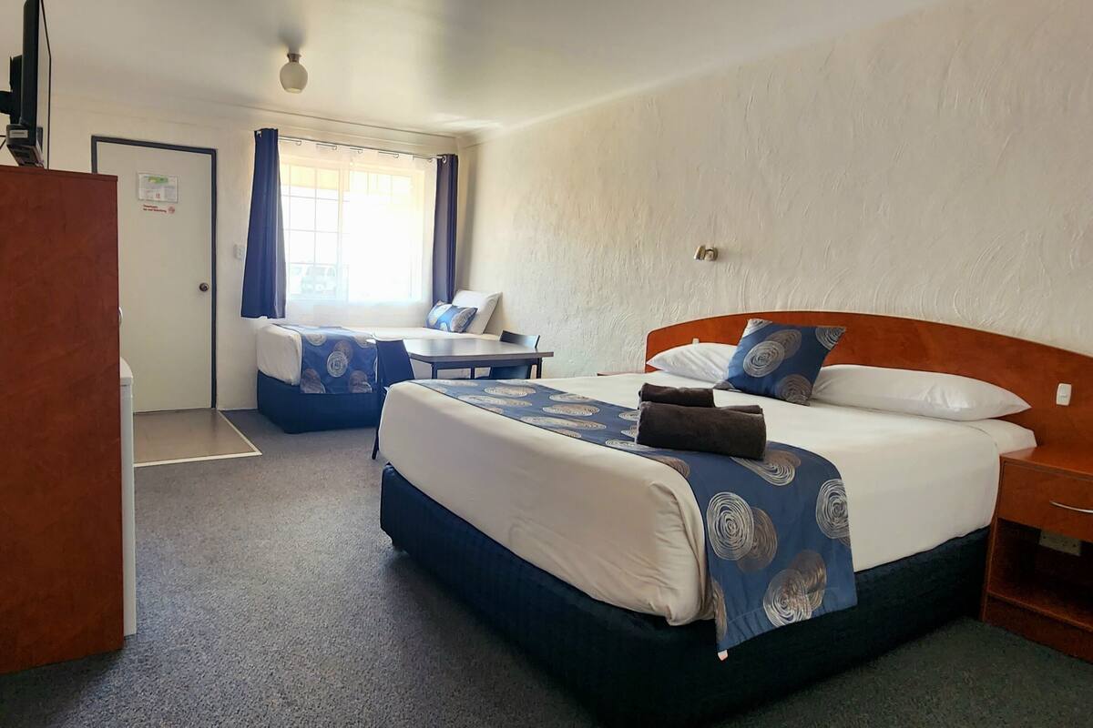 A hotel room with two beds, a desk, and a chair.