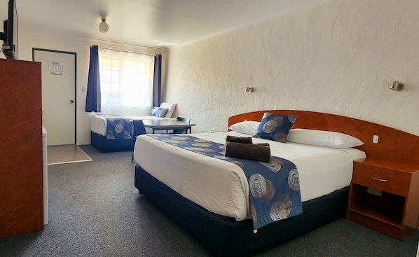 A hotel room with two beds, a desk, and a chair.