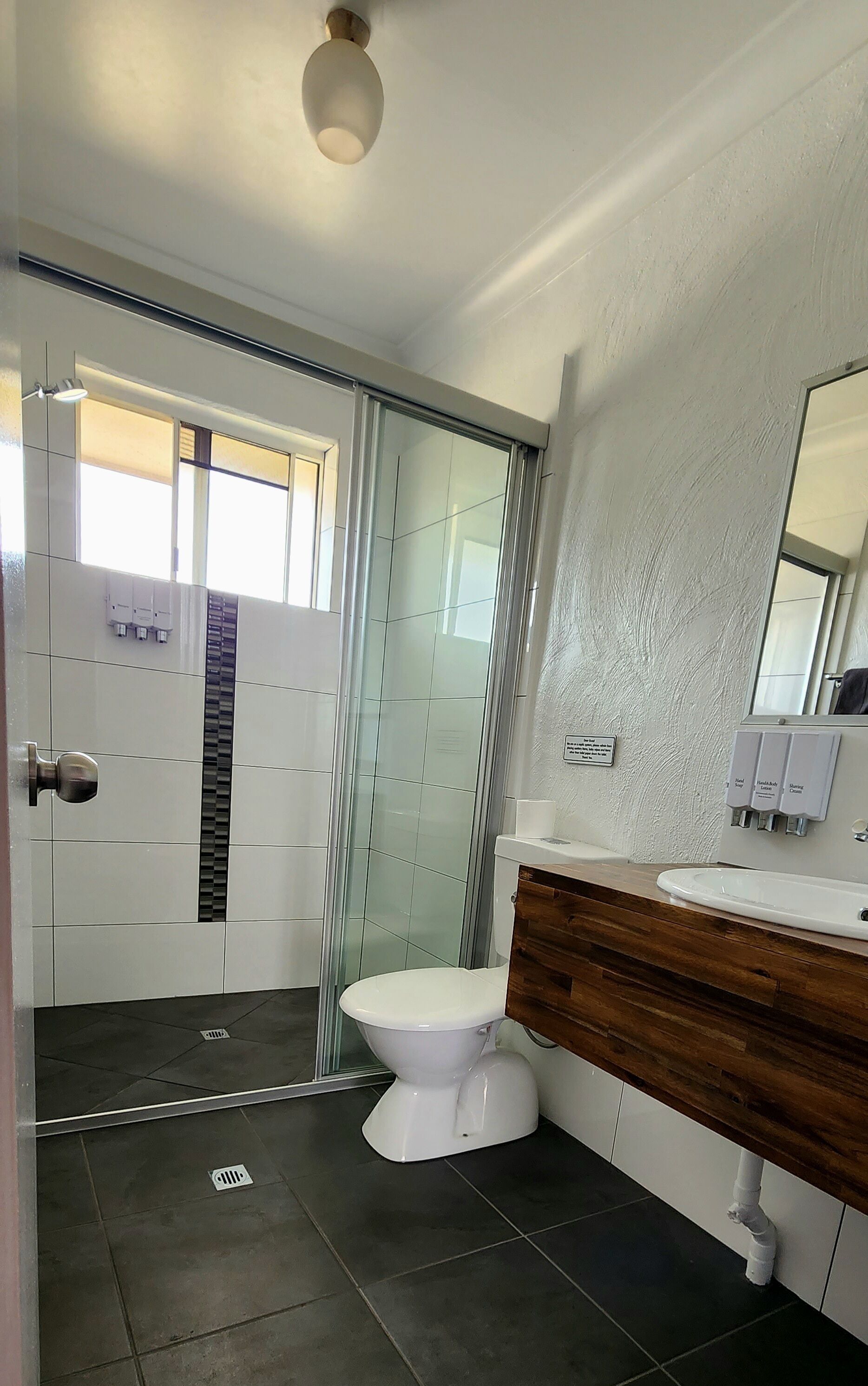 Een moderne badkamer met douche, toilet en wastafel.