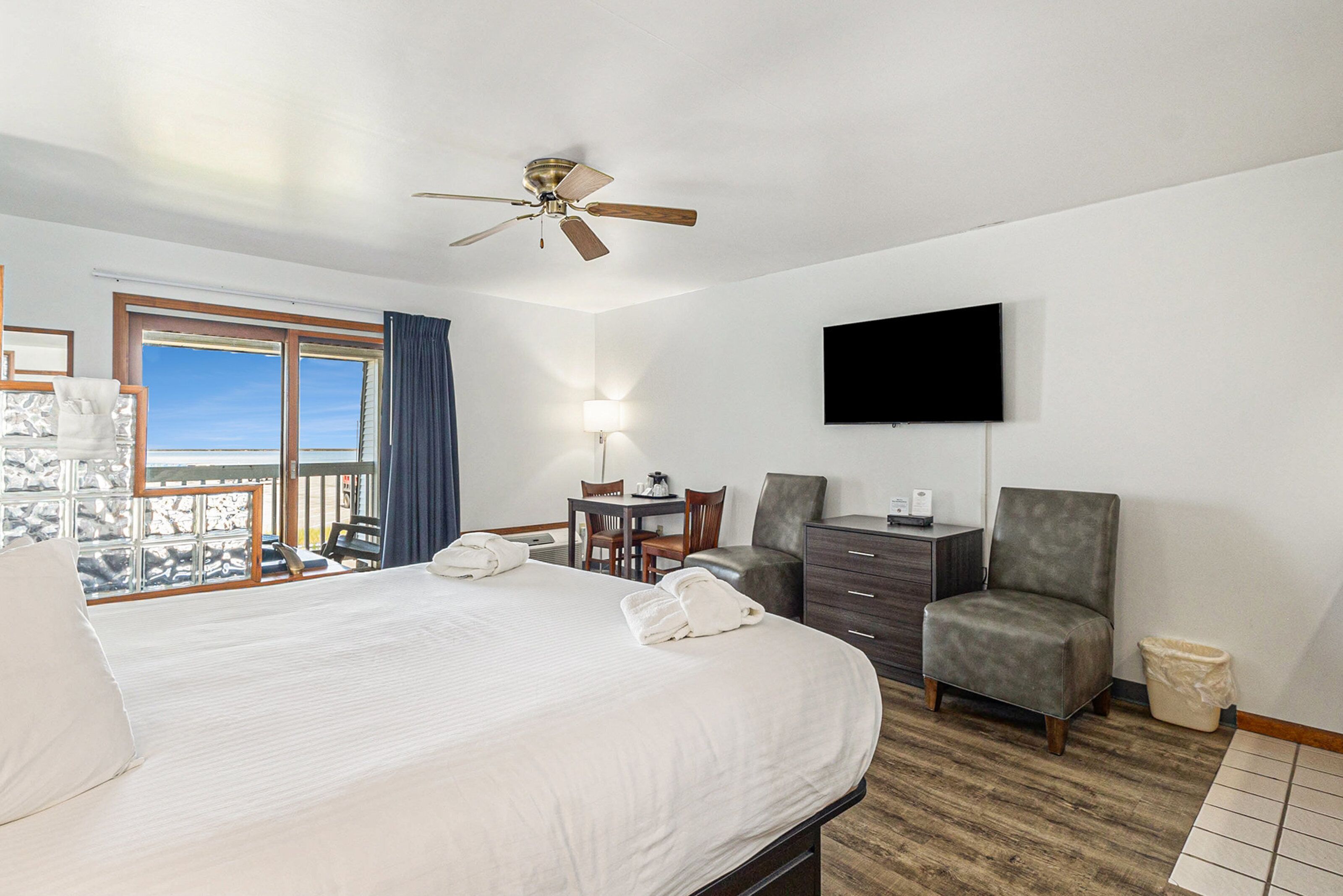 A hotel room with a bed, a desk, a chair, a television, and a view of the outdoors.