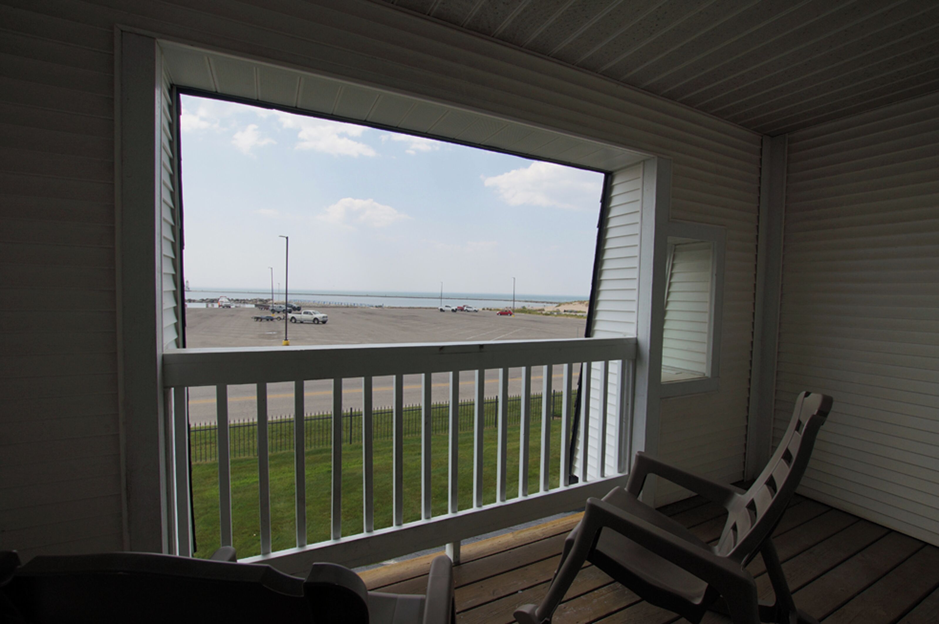 A room with a large window overlooking a parking area and a grassy field.