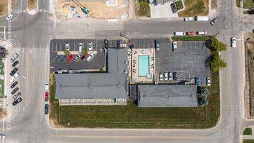 Vista aérea de un estacionamiento con varios coches, una piscina y un edificio de techo plano.