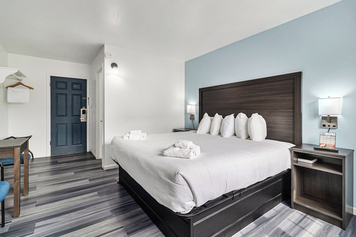 Quarto de hotel com uma cama grande, mesas de cabeceira, escrivaninha e uma cadeira.