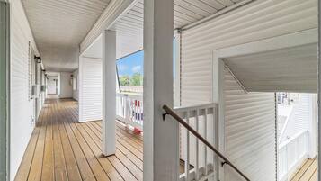 A covered wooden deck with white railings and a staircase.